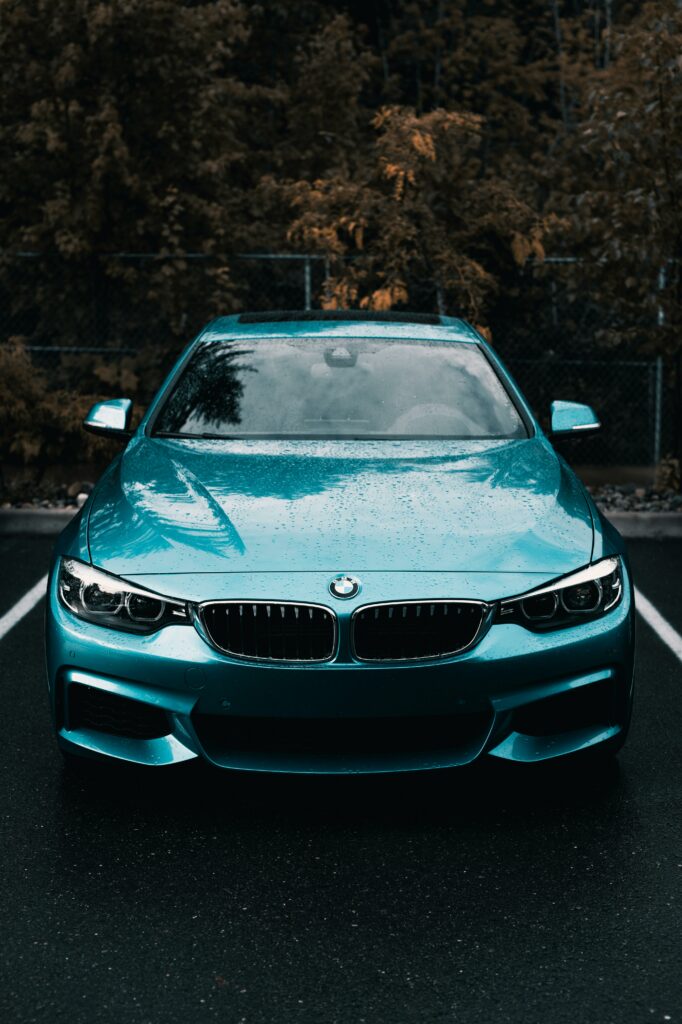 Front view of a luxurious blue car parked outdoors in a rainy parking lot in British Columbia, Canada.